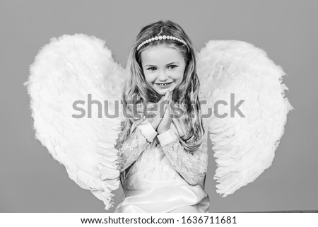 Valentines Day. Angel. Mischievous little angel girl standing with your clenched fists. Angels little hands crossed for you