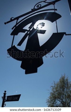silhouette of a hanging Windmill sign against the bright sunlight.
