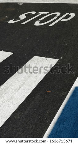 STOP written with paint on asphalt before an intersection in perspective from above. conceptual photo