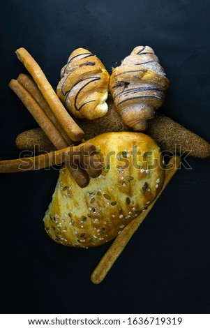 Different kinds of fresh bread with grain on black rustic background. Top views with clear space