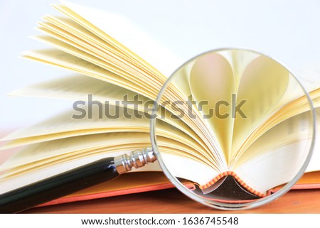 The image of the book that rolled into a heart shaped through the magnifying glass selective focus and shallow depth of field