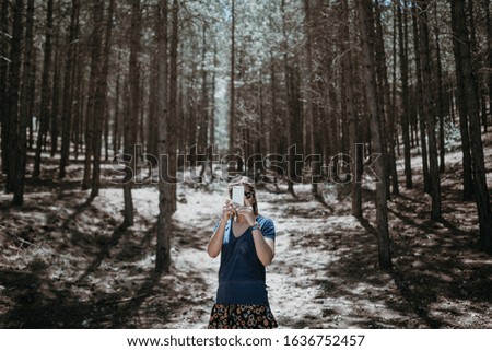 young woman taking a photo in a forest