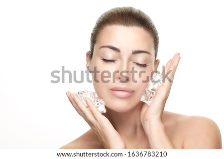 Beautiful spa Woman with healthy clean skin applies ice cubes on face. Cold Beauty Treatments. 