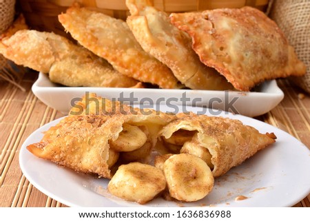 The brazilian fried sweet pastry sttufed with banana and cinnamon coverede with granulated sugar in a white plate on a straw base