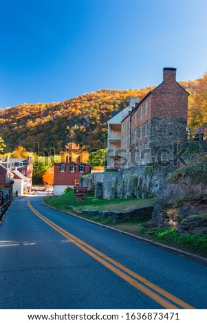 View of High Street in Harpers Ferry in West Virginia, USA with ancient Houses and  colorful Foliage on Trees in Background on a sunny Day