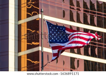 USA Flag. American flag. Flag of the United States flies waving beautifully in the strong wind. Background glass facade of modern office building.