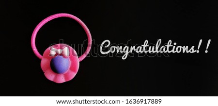 girl's pink rubber hair band with wording congratulations. 