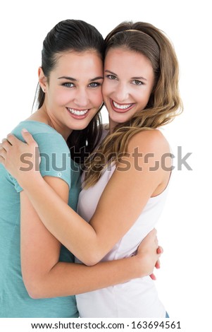 Side view portrait of a young female embracing her friend over white background