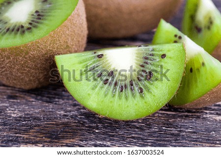 sliced into halves and pieces fresh sour or sweet green kiwi fruit on a wooden table, making a fruit dessert of exotic kiwi fruit
