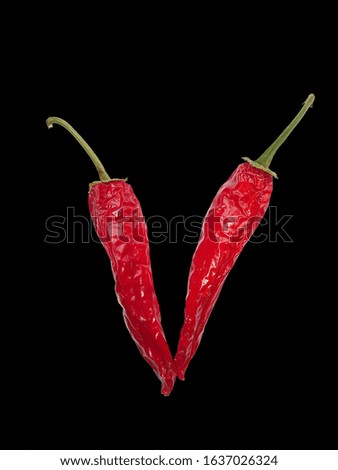 V letter of alphabet with red pepper isolated on a black background