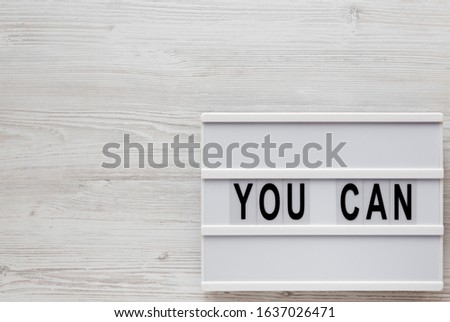 'You can' words on a lightbox on a white wooden surface, top view. Overhead, from above, flat lay. Space for text.