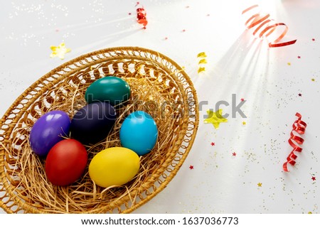 Multi-colored easter paint eggs in pottle and serpentine, confetti stars on light background. Unusial light and shadows. Festive easter concept.