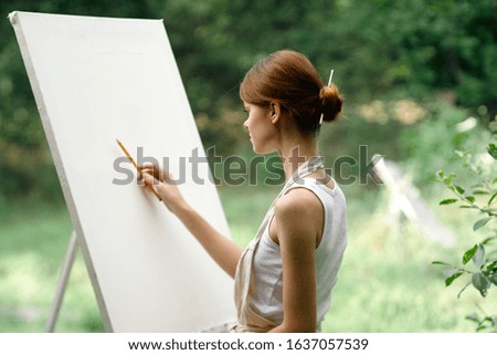 young easel woman draws a picture on the street