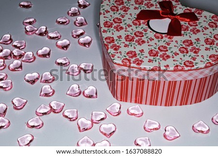 Heart shaped gift box with a red bow on the background of small pink hearts. Love heart frame. Happy mother's day concept. Love symbol. Holiday concept.