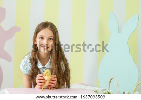 Easter composition. Nice girl with a chicken in her hands. Beautiful pink with blue pastel background.
