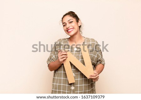 young pretty woman excited, happy, joyful, holding the letter N of the alphabet to form a word or a sentence.