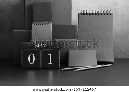 May 1st. Day 1 of month. Wood cube calendar with date month and day. Trendy classic black color. Lot of empty pages template for daily notes.