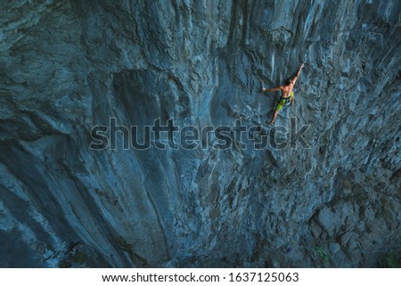 Powerful Rock climber climbing on a big rock wall 