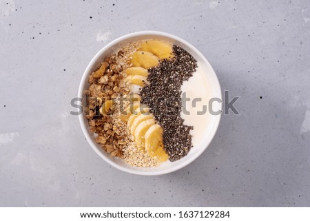 smoothie bowl with banana, Chia seeds, sesame and muesli on a grey background