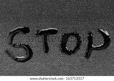 The word "STOP" on black skin is written by a liquid closeup