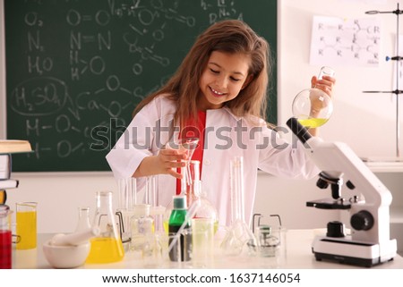 Schoolchild making experiment at table in chemistry class