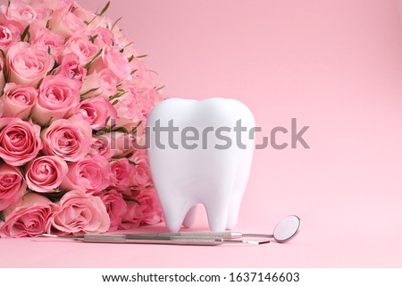 White tooth with dental instruments on a pink background with pink roses in honor of the international dentist day February 9 Royalty-Free Stock Photo #1637146603