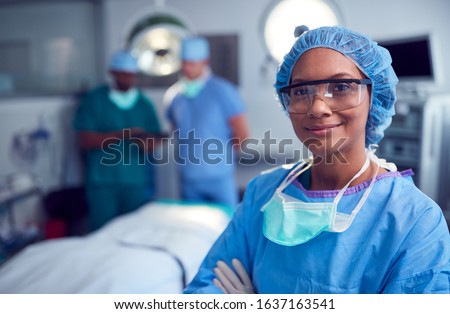 Portrait Of Female Surgeon Wearing Scrubs And Protective Glasses In Hospital Operating Theater Royalty-Free Stock Photo #1637163541