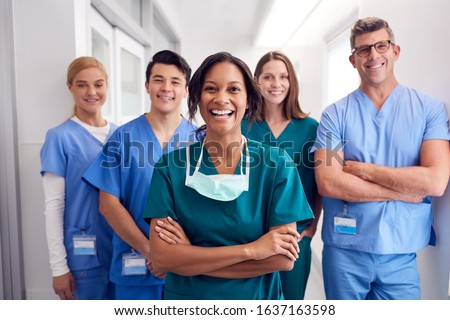 Portrait Of Laughing Multi-Cultural Medical Team Standing In Hospital Corridor