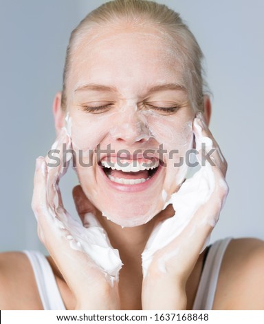 Pretty woman cleansing her face with water and soap. Beauty and skincare.