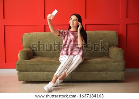 Young woman taking selfie while sitting on sofa at home