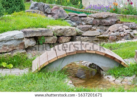 Modern garden design, rock garden with pond and bridge in summer