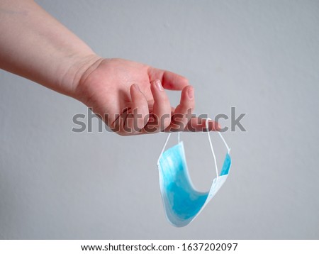 Female hand holds blue surgical mask with rubber ear straps. Typical three-layer surgical mask for covering the mouth and nose. (Clipping path). Protection concept
