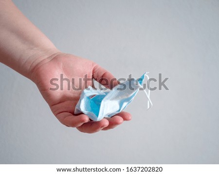 Female hand holds used crumpled surgical mask with rubber ear straps. Typical three-layer surgical mask for covering the mouth and nose. (Clipping path). Protection concept