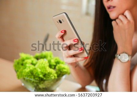 Woman eating salad and using her phone stock photo