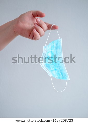 Female hand holds blue surgical mask with rubber ear straps. Typical three-layer surgical mask for covering the mouth and nose. (Clipping path). Protection concept