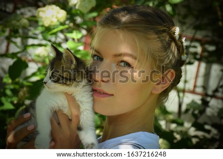 Beautiful young woman is holding cute little kitten in hands. Stock Photo