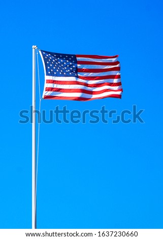 American flag on a blue background sky.  Flag blowing in the wind.  Stars and stripes. Stars and bars.  Flag pole