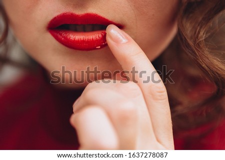 Red lips, girl wipes crumbs from her lips, finger near lips