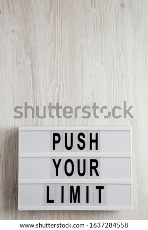 'Push your limit' words on a lightbox on a white wooden background, top view. Overhead, from above, flat lay. Copy space.