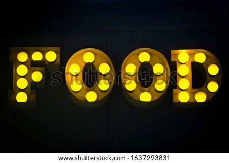 An old-fashioned "Food" sign with yellow lightbulbs.