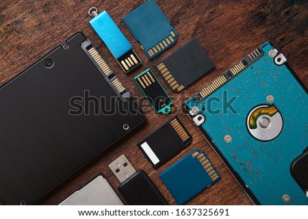 Memory Storage Gadgets. SSD, Hard Disk, SD Cards, Compact Flash and Flashdrive over rustic table.  Data drives. Royalty-Free Stock Photo #1637325691