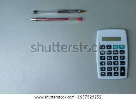 Calculator and red and black pen on a modern blue background