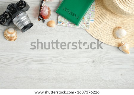 Top border of traveler accessories on wooden desk. Top view travel or vacation concept. Flat lay retro style camera, passport document, sunglasses, map, beach hat and seashells. Travel agency banner