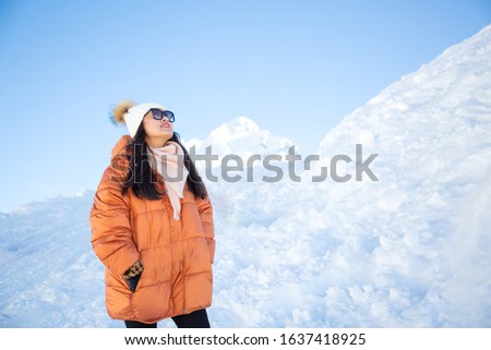 A picture of a beautiful woman looking at a mountain with a lot of snow happily as a holiday vacation and enjoying nature in the mountains. The famous GRINDELWALD-FIRST of Switzerland.