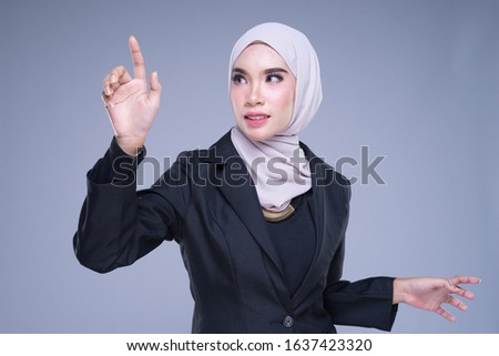 Half length portrait of an attractive Muslim businesswoman wearing hijab with tablet and gestures isolated on grey background. For image cutout for corporate, technology, business or finance.