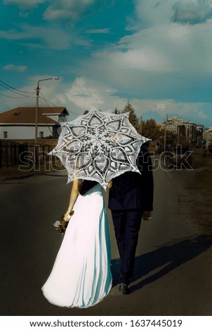 a couple of newlyweds walk under a white lace umbrella. The husband and wife. Bride and groom