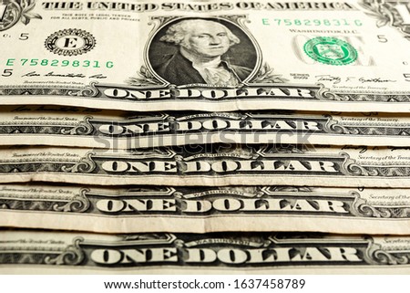 The inscription One Dollar. A row of 1 dollar bonds. Several American dollar bills with a portrait of President D. Washington close up. Bundle of USA cash.