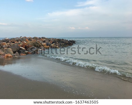 A picture of sea shore with small wave/ripple in the sunny day with clear blue sky and the rocky jetty for standing and watching beautiful beautiful natural scenery