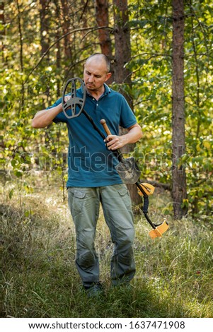 Man with electronic metal detector device, outdoor background.