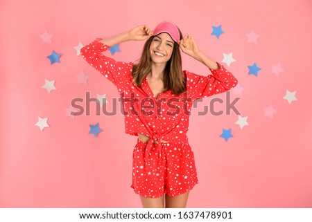 Beautiful woman wearing pajamas and sleep mask on pink background. Bedtime